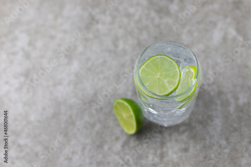 Refreshing drink, water with ice and lime on a gray background.