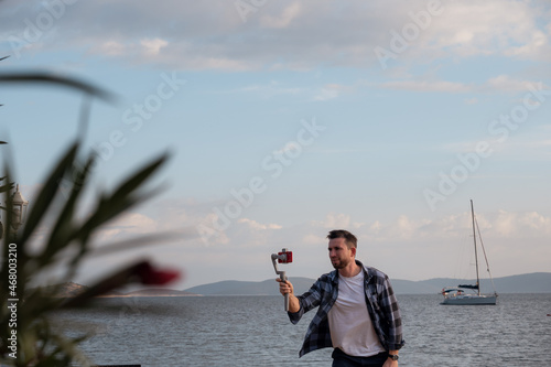 The use of technology. A male videographer shoots nature using a smartphone on a steadicam.