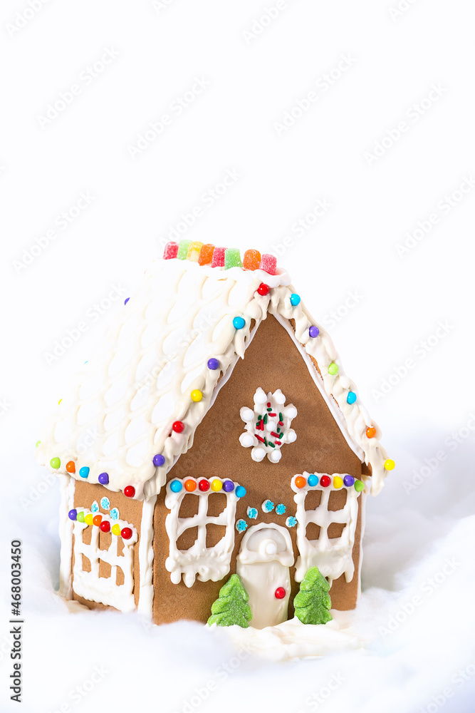 Christmas Gingerbread House displayed against white snowy background. Copy space.