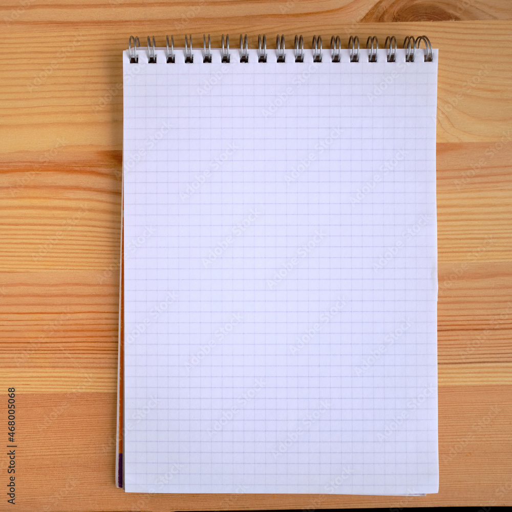 vertical blank copybook with metallic white spiral on a wooden background. Blank notepad mockup. Spiral notebook, secretary note pad template or background.. vertical blank copybook with metallic white spiral on a wooden background. Blank notepad mockup. Spiral notebook, secretary note pad template or background..