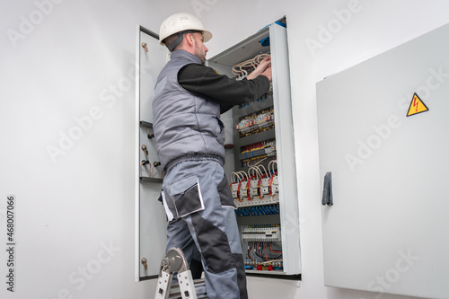 An electrician works in an electrical box. Engineer switches wires in power block