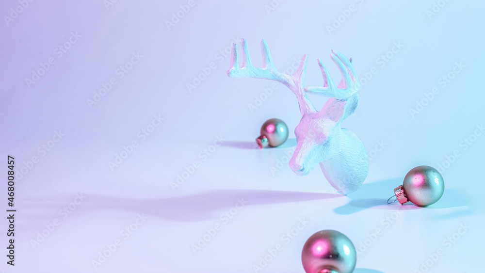 Christmas animal neon winter background. Holiday decoration bauble ball on neon gradient backdrop. Minimal abstract xmas reindeer. Happy new year copy space.