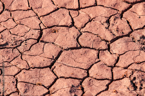 Cracked red earth during drought, the texture of earth during drought. A long time without rain. Infertile soil without plants