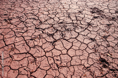 Cracked red earth during drought, the texture of earth during drought. A long time without rain. Infertile soil without plants
