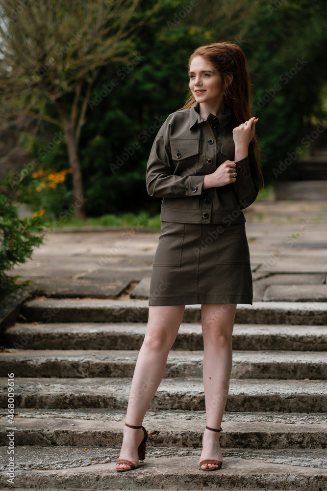 Attractive girl in a dark green suit standing in the park. Outdoor female portrait. Attractive girl in a dark green suit standing in the park. Outdoor female portrait.