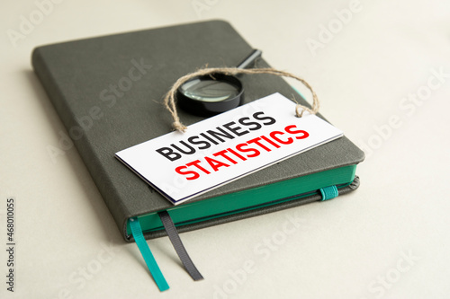 on the notebook is a magnifying glass and paper card with the inscription business statistics
