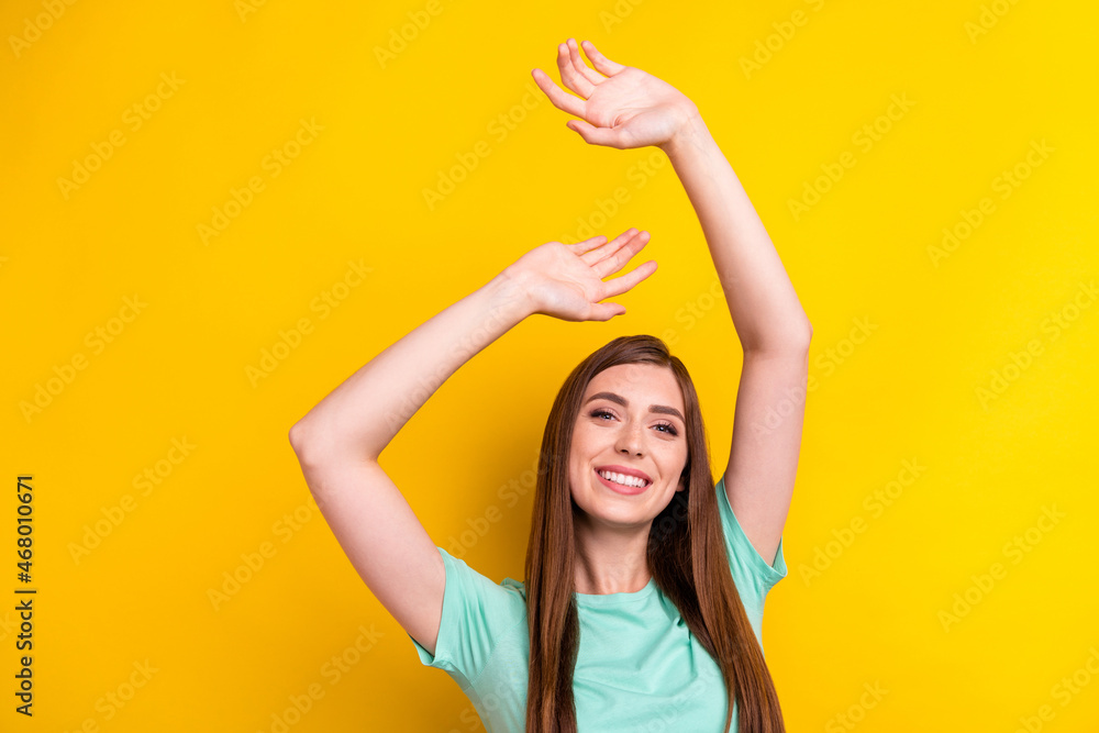 Photo of optimistic brunette hairdo young lady hands up wear teal t-shirt isolated on yellow color background Photo of optimistic brunette hairdo young lady hands up wear teal t-shirt isolated on yellow color background
