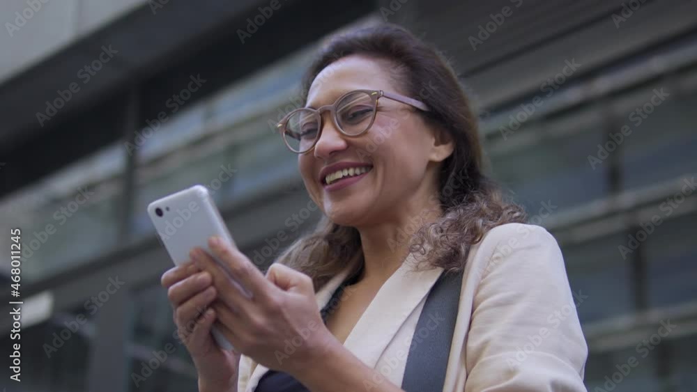 Woman in good mood looking at smartphone smiling, enjoying online communication Woman in good mood looking at smartphone smiling, enjoying online communication