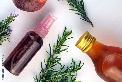 Rosemary and apple cider vinegar face toner in a bottle with spay, rosemary branches, apple cider vinegar bottle on white background. Flat lay photo