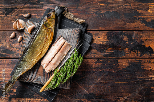 Fragrant Smoked herring fish fillet on wooden board with herbs. Wooden background. Top view. Copy space