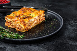 Lasagna with mince beef meat and tomato bolognese sauce on a plate. Black background. Top view. Copy space