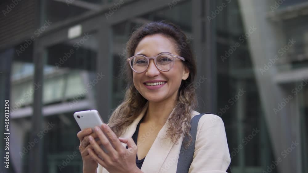 Happy business lady holding smartphone in hand, smiling at camera, technology Happy business lady holding smartphone in hand, smiling at camera, technology
