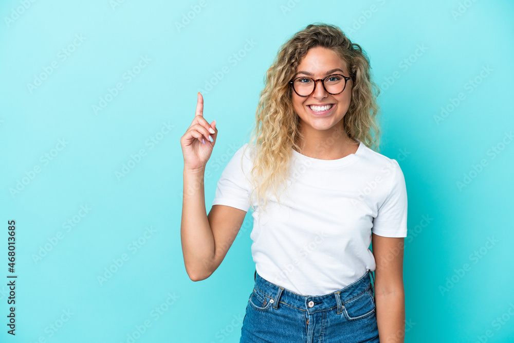 Girl with curly hair isolated on blue background pointing up a great idea Girl with curly hair isolated on blue background pointing up a great idea