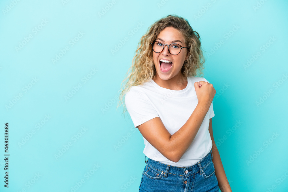 Girl with curly hair isolated on blue background celebrating a victory Girl with curly hair isolated on blue background celebrating a victory