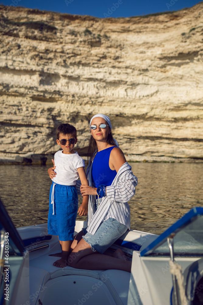 mother and son in a swimsuit sitting on the bow of speedboat in the summer on vacation