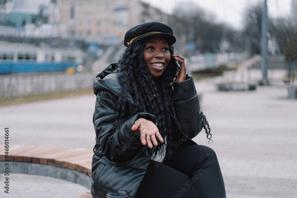 Afro girl uses the phone on the outdoors. Happy urban afro american girl hold smartphone. People using technology Afro girl uses the phone on the outdoors. Happy urban afro american girl hold smartphone. People using technology
