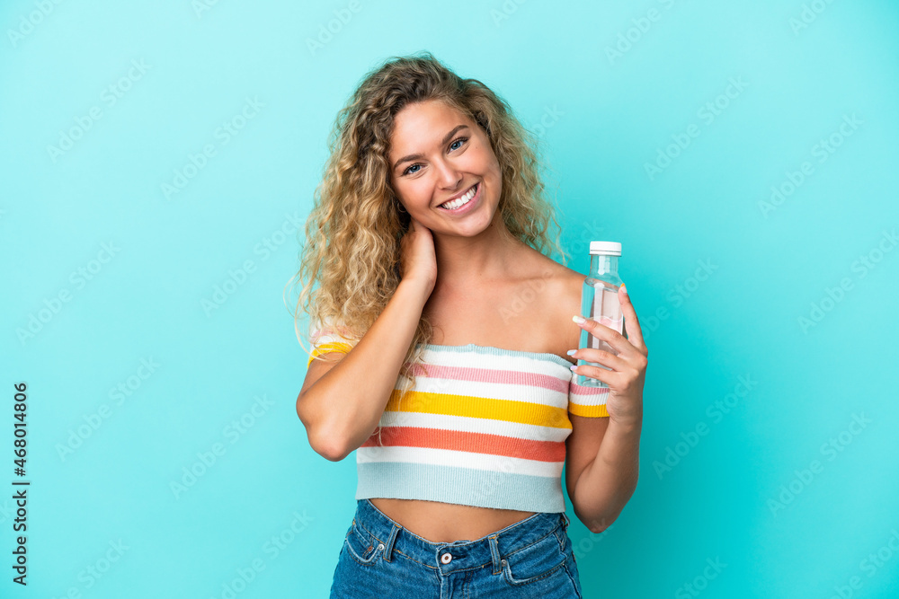 Young blonde woman with a bottle of water isolated on blue background laughing Young blonde woman with a bottle of water isolated on blue background laughing