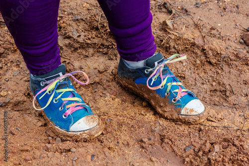 A young girl with colorful muddy shoes from playing outside.