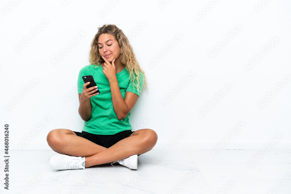 Girl with curly hair sitting on the floor thinking and sending a message Girl with curly hair sitting on the floor thinking and sending a message