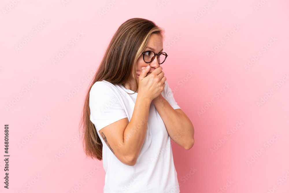 Young English woman isolated on pink background covering mouth and looking to the side Young English woman isolated on pink background covering mouth and looking to the side