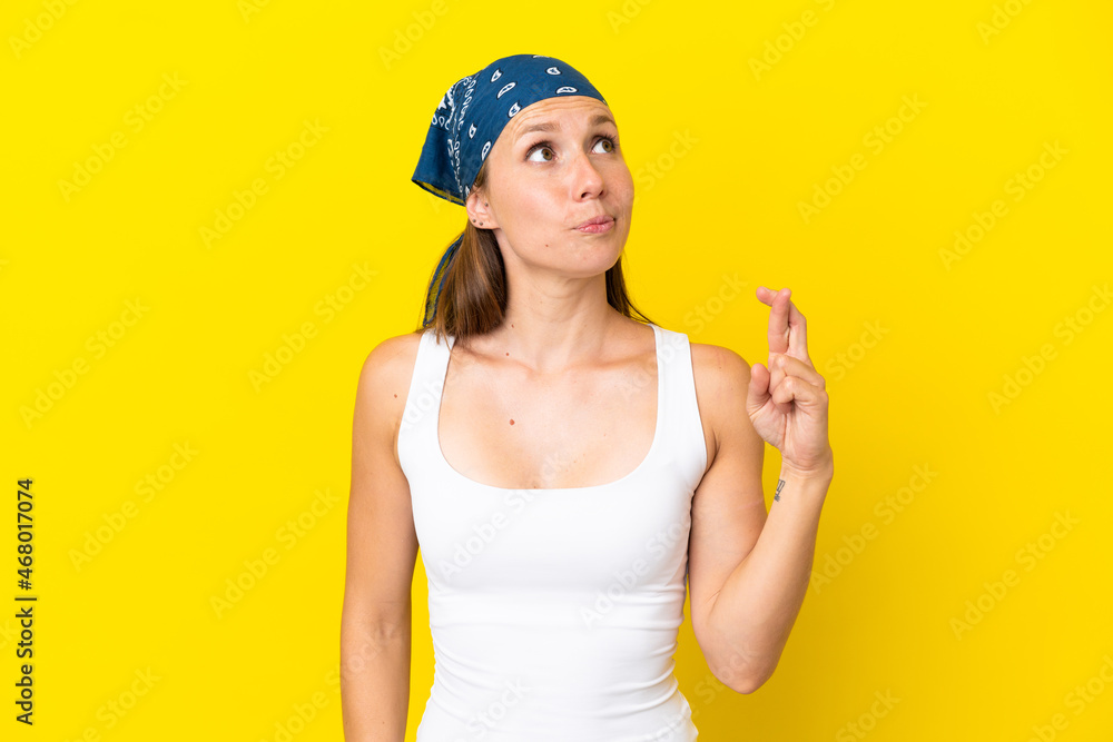 Young English woman isolated on yellow background with fingers crossing and wishing the best Young English woman isolated on yellow background with fingers crossing and wishing the best