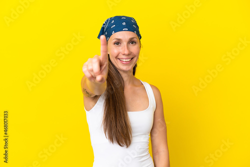Young English woman isolated on yellow background showing and lifting a finger