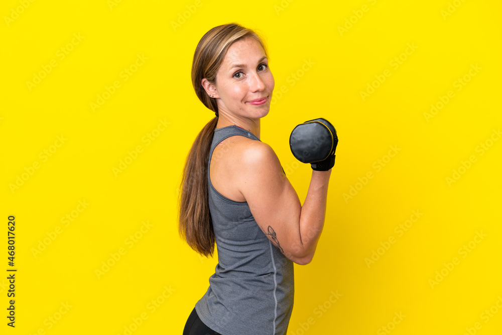 Young English woman isolated on yellow background making weightlifting Young English woman isolated on yellow background making weightlifting