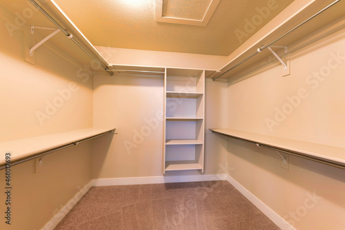 Empty walk-in closet with warm color lighting and shelving units