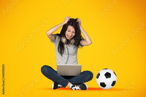 Portrait of happy girl watching football game online on her laptop © BillionPhotos.com