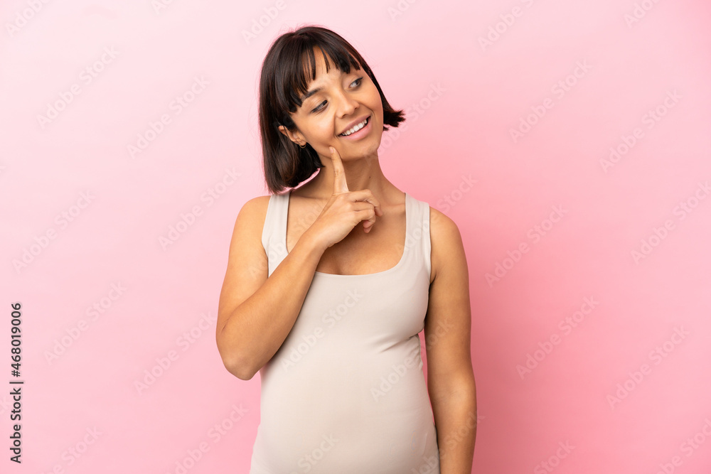 Young pregnant woman over isolated pink background thinking an idea while looking up Young pregnant woman over isolated pink background thinking an idea while looking up