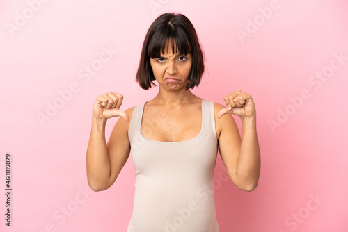 Young pregnant woman over isolated pink background showing thumb down with two hands