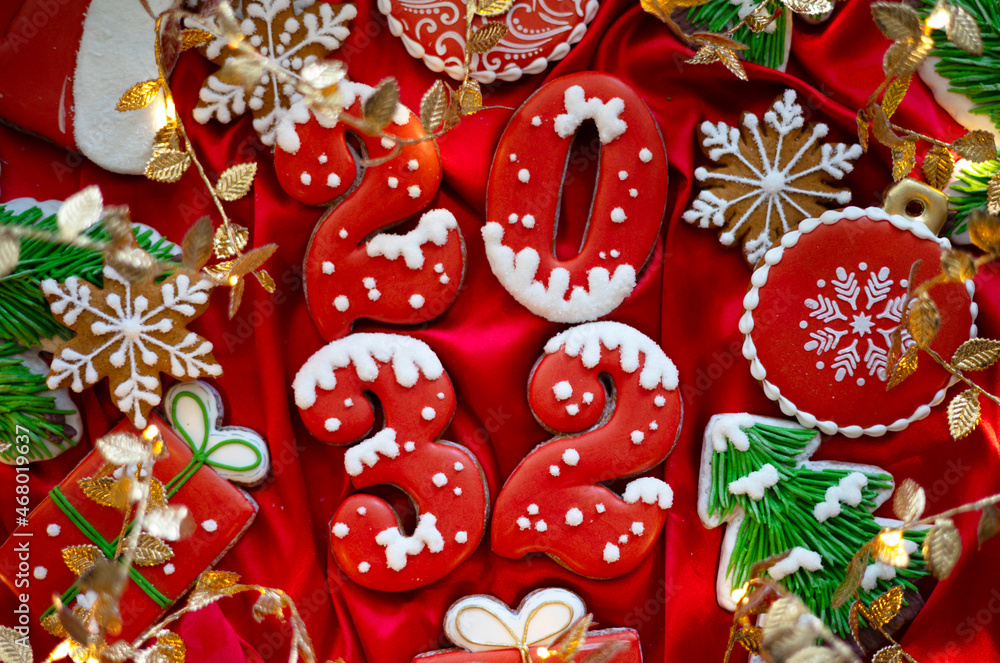 Banner for Christmas and New Year gingerbread cookies numbers 2032, snowflakes, Santa hat, Christmas trees, garlands on red silk fabric background