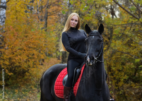 Beautiful girl ride her horse in autumn forest at sunset