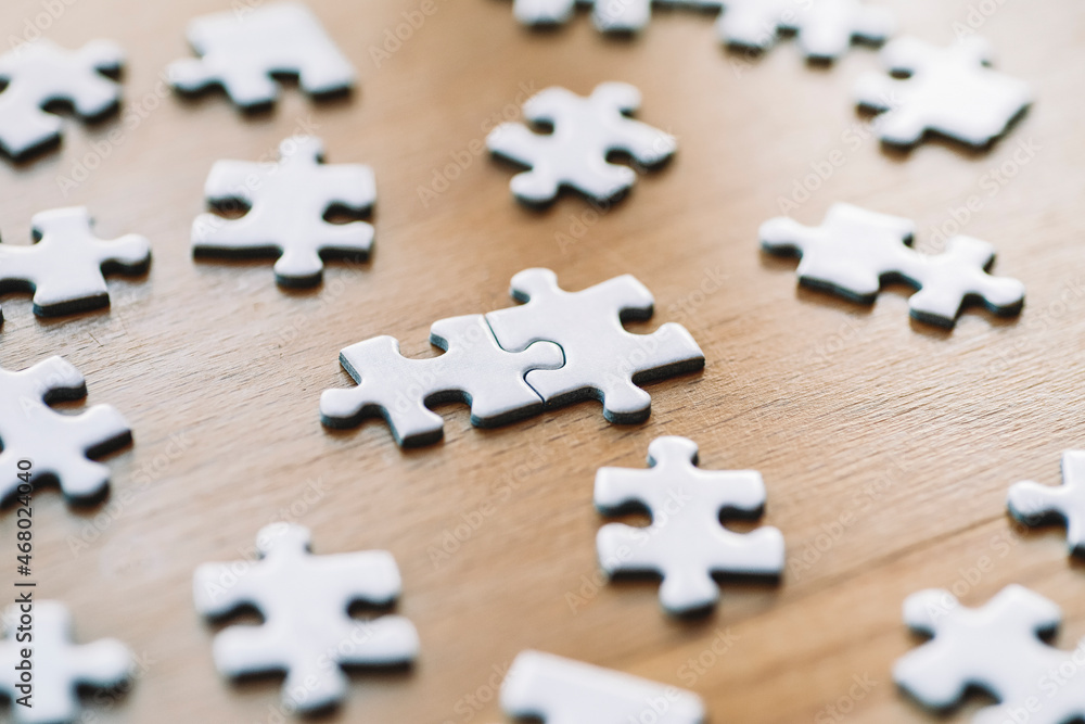Obraz premium Puzzle pieces are connected. White puzzle pieces on a wooden table background. Business, partner, solution, alliance, union concept.