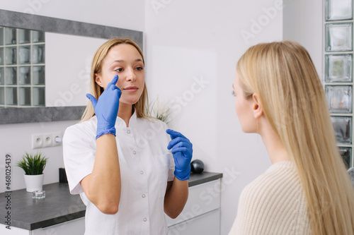 Consultation in cosmetology clinic. Female professional beauty doctor talking with pretty young female.