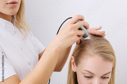 Doctor diagnoses the structure of the hair. Consultation with a trichologist