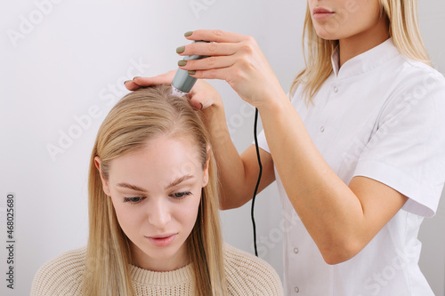 Doctor diagnoses the structure of the hair. Consultation with a trichologist