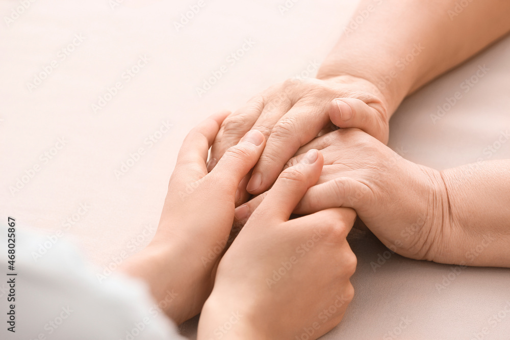 Young woman holding hands of grandmother at table