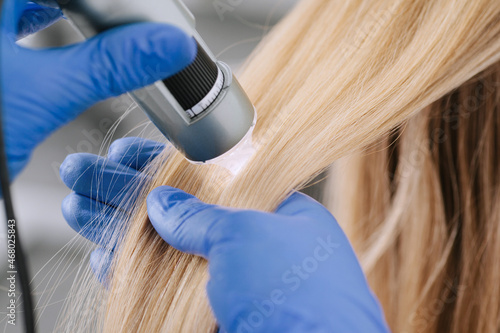 Doctor diagnoses the structure of the hair. Consultation with a trichologist