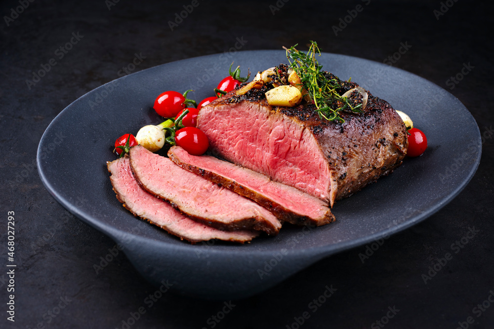 Modern style traditional Commonwealth Sunday roast with sliced cold cuts roast beef with tomatoes and scallions as top view in a design plate Modern style traditional Commonwealth Sunday roast with sliced cold cuts roast beef with tomatoes and scallions as top view in a design plate