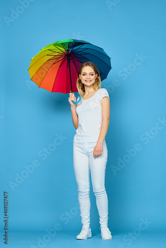 fashionable woman with umbrella rainbow colors posing blue background