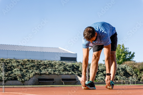 athletic young man stretching calves before start running