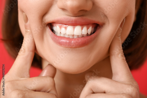 Young woman with healthy gums on color background, closeup