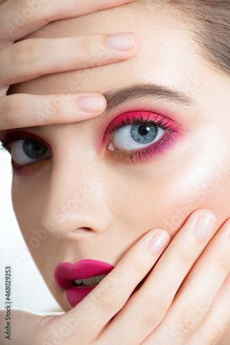 Closeup of beautiful young woman   s face with perfect skin  long eyelashes and bright vivid pink make up. Portrait of fashion beauty model with colorful professional makeup. Macro  selective focus