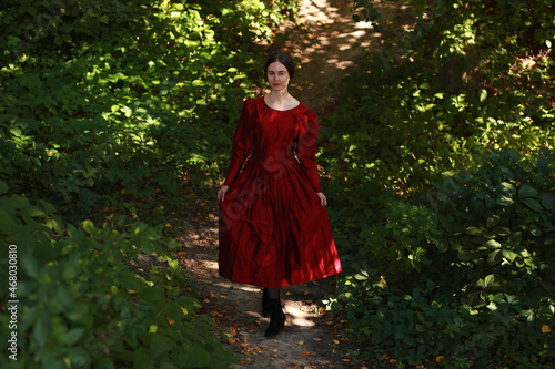 Woman in red dress standing on a path in the forest