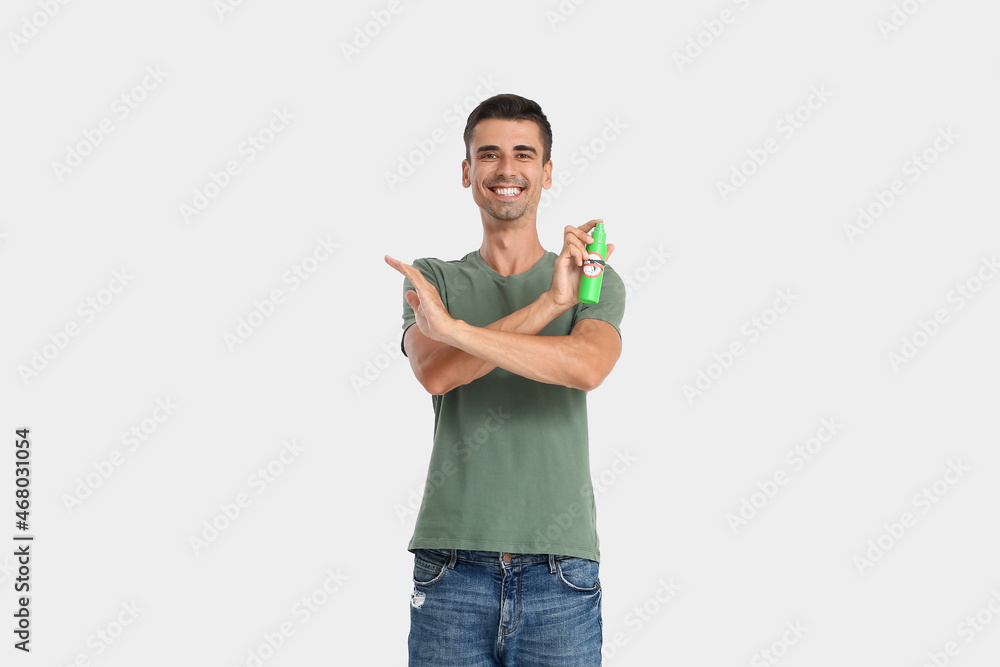 Young man with mosquito repellent on light background Young man with mosquito repellent on light background