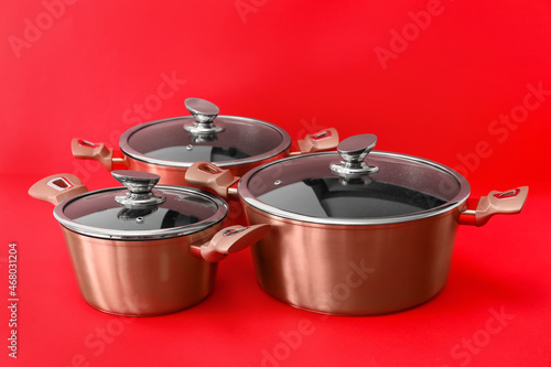 Steel cooking pots on color background