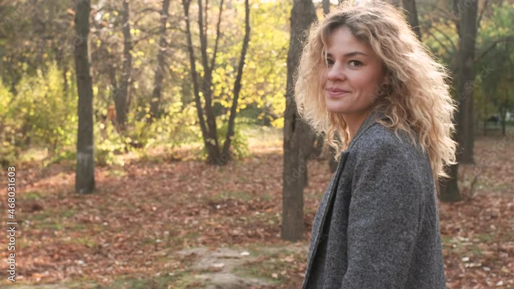 Portrait of young attractive curly woman walking in the autumn park on a sunny day Portrait of young attractive curly woman walking in the autumn park on a sunny day
