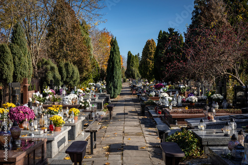 A cemetery alley in autumn. Memorial candle lights and flowers on the graves. 