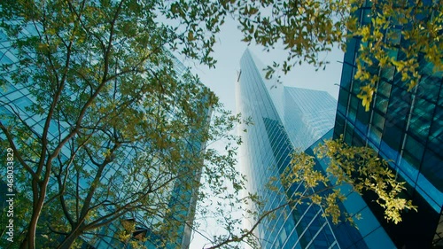 Nature vs Culture: Paris Downtown with Modern Skyscrapers and Glass Office Buildings seen through Green Trees. Business District with Corporate Skyline and Futuristic Cityscape. 4K Wide low angle shot